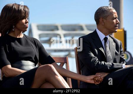 Präsident Barack Obama und First Lady Michelle Obama halten sich die Hände, während sie den Rep. John Lewis, D-Ga. Während einer Veranstaltung zum Gedenken an den 50th. Jahrestag des Blutigen Sonntags und der Bürgerrechtsmärsche von Selma nach Montgomery, an der Edmund Pettus Brücke in Selma, Alabama, am 7. März 2015, hören. Stockfoto