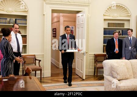 Präsident Barrack Obama trägt einen Kuchen in die Oval Office Geburtstagsfeier für Phil Schiliro, Assistent des Präsidenten für legislative Angelegenheiten, 6. August 2009 Stockfoto