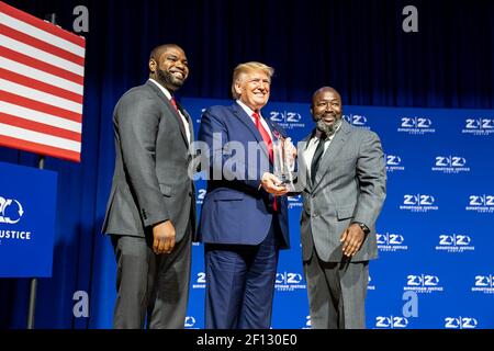 Präsident Donald Trump wird mit einem Preis von Florida State Rep. Byron Donalds links und Matthew Charles einer der ersten Insassen, die von der First Step Act von 2018 auf dem 2019 Second Step Presidential Justice Forum Freitag 25 2019. Oktober im Benedict College in Columbia S.C. profitieren Stockfoto