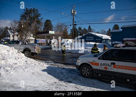 Unfallort des Fahrzeugs mit Feuerwehrleuten, die den Verkehr leiten, einem Krankenwagen und EMT im Bereitschaftszustand und einem Lastwagen, der im Schneefall feststeckt. Stockfoto