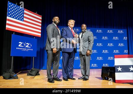 Präsident Donald Trump wird mit einem Preis von Florida State Rep. Byron Donalds links und Matthew Charles einer der ersten Insassen, die von der First Step Act von 2018 auf dem 2019 Second Step Presidential Justice Forum Freitag 25 2019. Oktober im Benedict College in Columbia S.C. profitieren Stockfoto