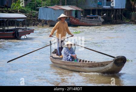 Vietnamesischer Mann und Frau in konischen Hüten auf einem Kanuboot, Rudern. Cai Be, Provinz Tien Giang, Mekong Delta, Vietnam Stockfoto