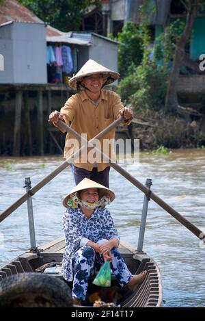 Vietnamesischer Mann und Frau in konischen Hüten auf einem Kanuboot, Rudern. Cai Be, Provinz Tien Giang, Mekong Delta, Vietnam Stockfoto