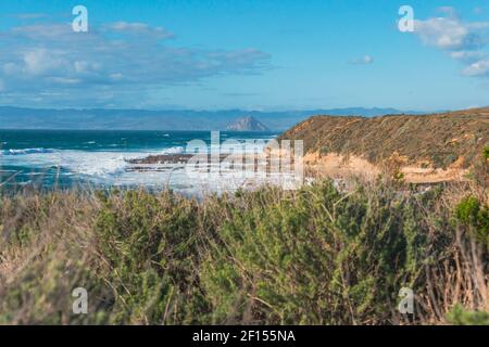 Pazifischer Ozean, felsige Klippen und Silhouette von Morro Rock. Blick vom Montana del Oro State Park, kalifornische Küste Stockfoto