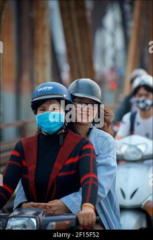 Vietnamesische Stadtpendler auf Motorrädern über die historische lange Bien-Brücke, Hanoi, Vietnam. Zwei Frauen reiten Pillion Stockfoto