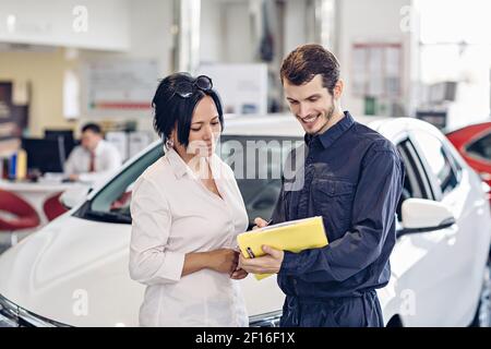 Car Service Center Szene. Der Mechaniker kommuniziert mit dem Kunden Stockfoto