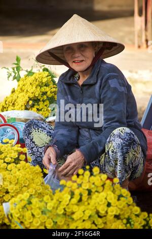 Vietnamesische Frau in unverwechselbaren konischen Hut Verkauf Blumen auf Hoi an Markt, Vietnam Stockfoto