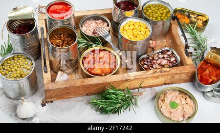 Verschiedene Gemüsekonserven, Fisch und Erbsen in Aluminiumdosen. Auf hellgrauem Hintergrund. Stockfoto