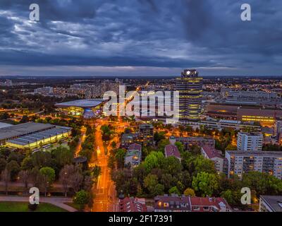 Wunderbarer Blick in die Dämmerung über das beleuchtete München mit Geschäftsviertel und Autos auf der Straße aus einer hohen Perspektive. Stockfoto