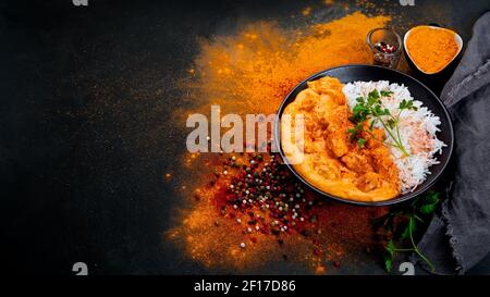 Indisches Butterhuhn-Curry mit Basmati-Reis auf dunklem Hintergrund. Traditionelles hausgemachtes Lebensmittelkonzept. Platz kopieren Stockfoto