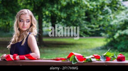 Schönes Mädchen mit Rose und rotem Band Stockfoto