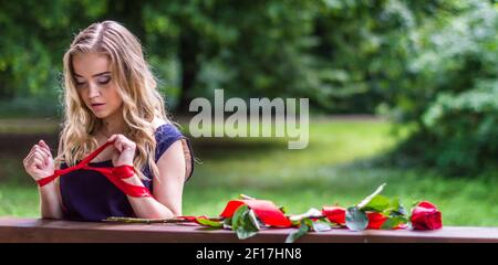 Schönes Mädchen mit Rose und rotem Band Stockfoto