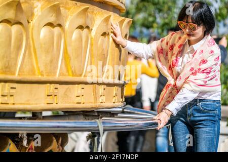 Shangrila China , 8. Oktober 2020 : Chinesische Touristenfrau posiert mit dem riesigen tibetisch-buddhistischen Gebetsrad des Dafo-Tempels in Shangri-La Yunnan China Stockfoto