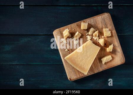 Zerbröckelter Parmesankäse, von oben auf einem dunkelblauen Holzhintergrund mit Kopierfläche aufgenommen Stockfoto