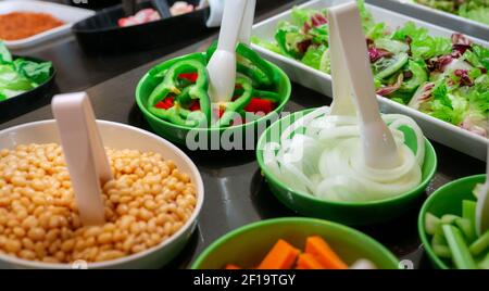 Salatbuffet im Restaurant. Frisches Salatbuffet zum Mittag- oder Abendessen. Gesunde Ernährung. Grüner und roter Pfeffer und Zwiebeln in grüner Schüssel auf der Theke. Stockfoto