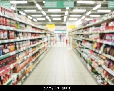 Verschwommenes Supermarktschiff mit bunten Regalen von Waren. Perspektivische Ansicht des abstrakten Supermarktschiffs mit Kopierfläche in der Mitte, kann als Hintergrund oder Retail-Konzept Stockfoto