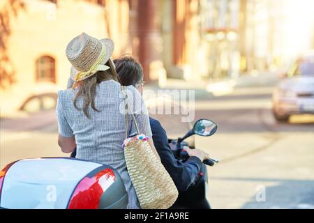 Glückliches reifes Paar, das einen Roller in der Stadt auf fährt Ein sonniger Tag Stockfoto