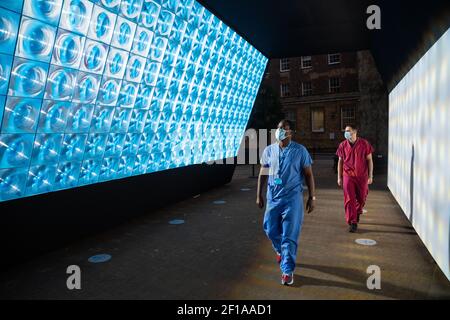 Trauma- und Orthopädiechirurg Frank Acquaah (links) und 3rd-jähriger Medizinstudent Imade Remmouche schauen sich den Tunnel of Light im GuyÕs und St. ThomasÕ Hospital in London an. Der speziell angefertigte Tunnel ist eine immersive Kunstinstallation, die speziell entwickelt wurde, um die Illusion und Perspektive einer Millionen Meilen entfernten neuen Sonne in einem wolkenlosen Himmel zu erzeugen. Bilddatum: Samstag, 6. März 2021. Stockfoto