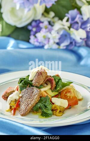 Fleischsalat mit grünen Tomaten auf dem Teller blauer Hintergrund Viele Rezepte für Lebensmittel Stockfoto