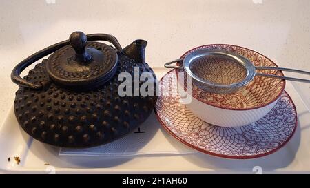 Tee serviert in einer dekorativen Topf mit Sieb über Tasse Und Untertasse Stockfoto