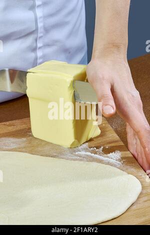 Der Koch schneidet ein großes Stück Butter auf dem Teig Vorbereitung Käsekuchen Serie voll Kochen Lebensmittel Rezepte Stockfoto