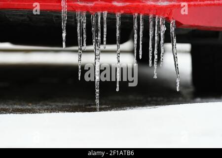 Schöne Eiszapfen auf dem Auto. Konzept für den Winter- und gefährlichen Winterverkehr von Autos auf der Straße. Stockfoto