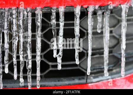 Schöne Eiszapfen auf dem Auto. Konzept für den Winter- und gefährlichen Winterverkehr von Autos auf der Straße. Stockfoto