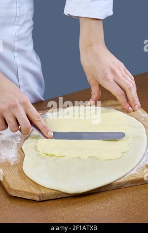 Der Koch schmiert Butter auf den Teig für die Zubereitung Backen Kochen Stockfoto