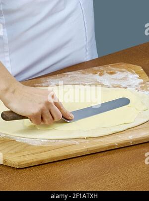 Der Koch schmiert Butter auf den Teig für die Zubereitung Backen Kochen Stockfoto