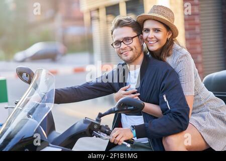 Glückliches reifes Paar, das einen Roller in der Stadt auf fährt Ein sonniger Tag Stockfoto