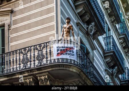 Ein katalanisches Protestbanner und eine Skulptur in Barcelona, Katalonien, Spanien. Der Text sagt "Freiheit für politische Gefangene". Stockfoto