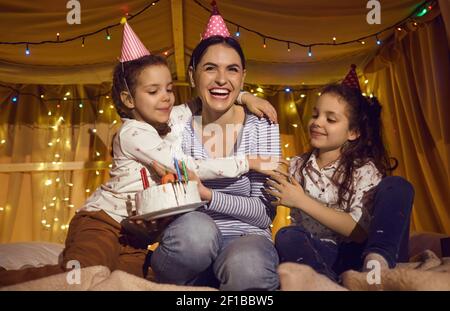 Glückliche junge Mutter feiert ihren Geburtstag mit ihrem niedlichen kleinen Töchter zu Hause Stockfoto