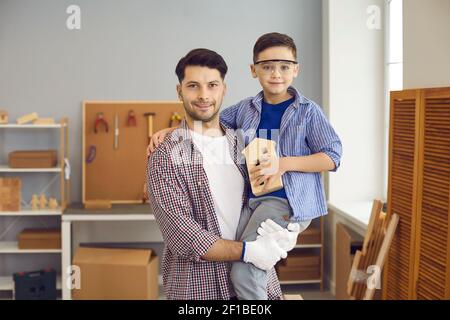 Familienportrait des jungen Vaters mit seinem Lieblings-kleinen Sohn in der Werkstatt oder Garage zu Hause. Stockfoto