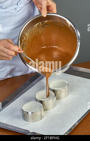 Der Koch gießt den Teig in Formen für die Herstellung von Cupcakes Stockfoto