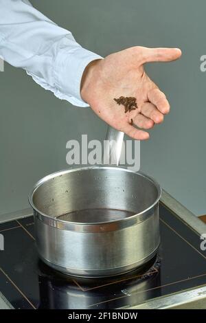 Der Koch nippt die Zutaten zum Kochen in einer Pfanne Glühwein voller kulinarischer Rezepte Stockfoto