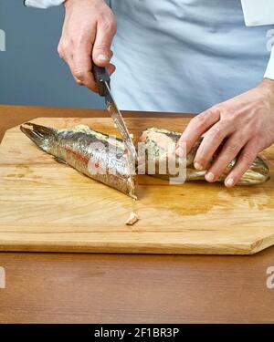 Der Koch schneidet den gebackenen Fisch eine vollständige Sammlung von Speiserezepte Stockfoto