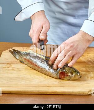 Der Koch schneidet den gebackenen Fisch eine vollständige Sammlung von Speiserezepte Stockfoto