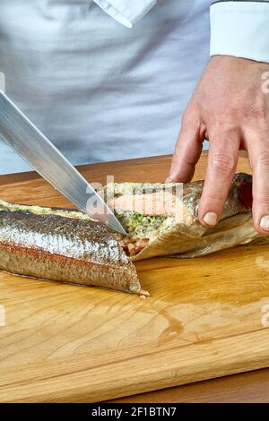 Der Koch schneidet den gebackenen Fisch eine vollständige Sammlung von Speiserezepte Stockfoto