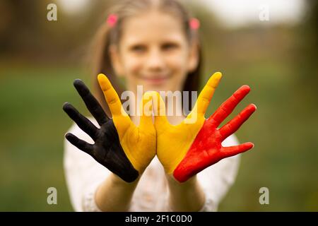 Kind Mädchen zeigen Hände in Belgien Flagge Farben zu Fuß im Freien gemalt, konzentrieren sich auf die Hände Stockfoto