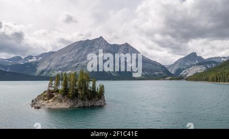 Isolierte Insel auf alpinem See mit Bergen im Hintergrund. Aufgenommen am Upper Kananaskis Lake Trail, Alberta, Kanada Stockfoto