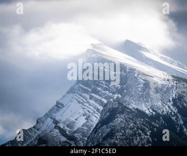 Schneebedeckter Berggipfel (Mount Rundle), bedeckt von Schnee und von Wolken und Winden, detaillierte Aufnahme aus Vermilion Lakes, Banff National Park, Kanada Stockfoto