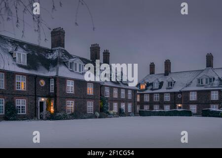 Europa, Großbritannien, England, London, Barnett, Reihenhäuser im Stil von Kunsthandwerk in Hampstead Garden Vorort. Winter mit Schnee, warmes Leuchten aus den Fenstern Stockfoto