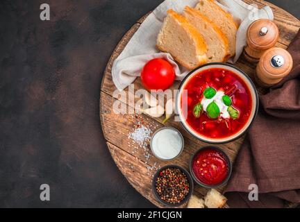Tomatensuppe mit frischer Sauerrahm. Traditionelles Borscht auf braunem Betongrund. Das Konzept der traditionellen Gerichte. Stockfoto