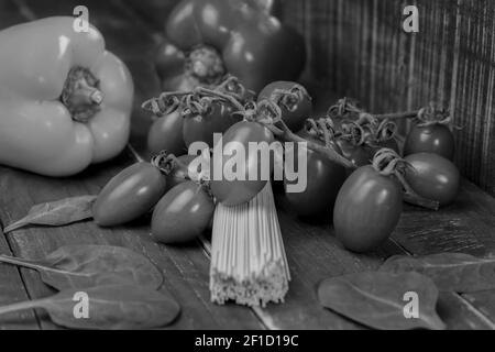 Schwarz-weiß Nahaufnahme von rohen Pasta Spaghetti auf Holzhintergrund.frisches Bio-Gemüse mit ungekochter Pasta, gesundes Lebensmittelkonzept. Stockfoto