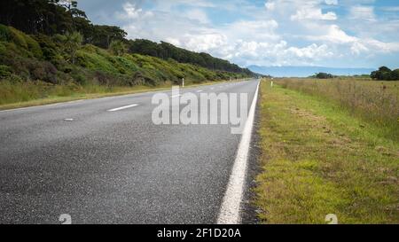 Straße, die in die Ferne führt (gerader Horizont). Aufgenommen an sonnigen Tagen an der Westküste Neuseelands Stockfoto