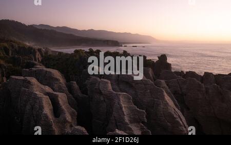 Ungewöhnliche Felsformationen an der Küste des Ozeans während Sonnenuntergang aufgenommen, Bild gemacht´s Punakaiki Pancake Rocks, Westküste, Neuseeland Stockfoto