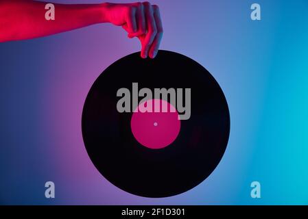 Hand halten Retro Vinyl Disc mit Neonlicht Stockfoto