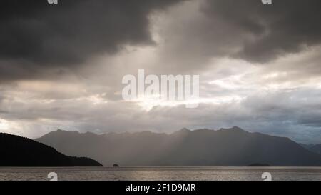 Sturmwolken sammeln sich über dem See und der Bergkette, aufgenommen am Kepler Track, Fiordland National Park, Neuseeland Stockfoto