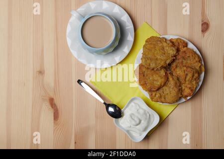 Kartoffelpfannkuchen auf einem Teller und eine Tasse Kaffee Auf einem hölzernen Hintergrund Stockfoto