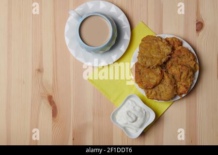 Kartoffelpfannkuchen auf einem Teller und eine Tasse Kaffee Auf einem hölzernen Hintergrund Stockfoto